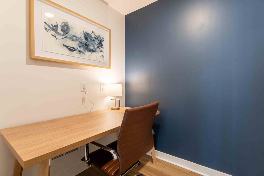 a home office with a wooden desk and a blue wall