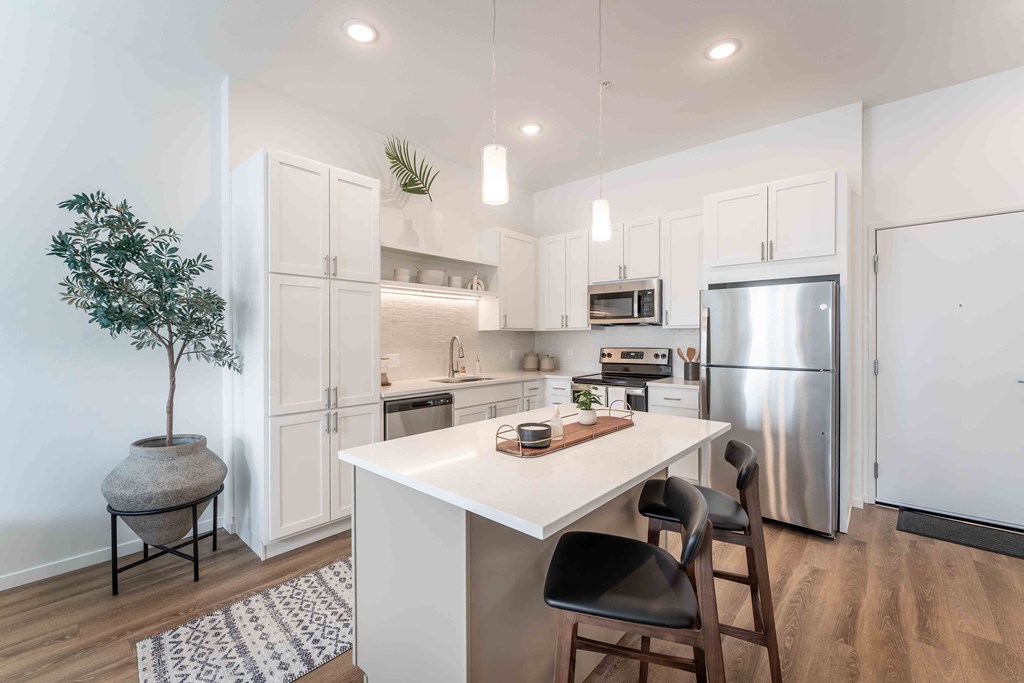 a white kitchen with stainless steel appliances and a white counter top