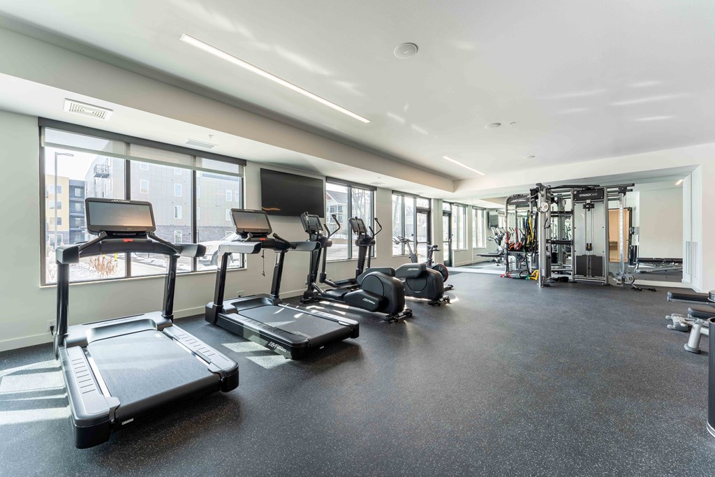 a gym with cardio equipment and windows in a building