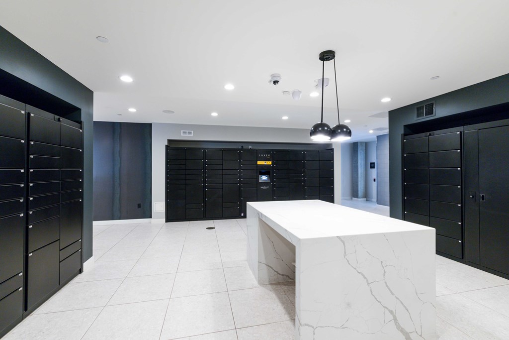 A white marble table is in the middle of a room with black lockers on the walls.