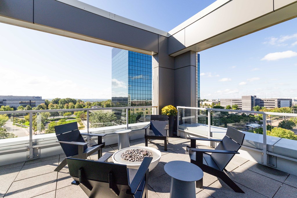 A patio with chairs and a table with a vase of flowers on it.