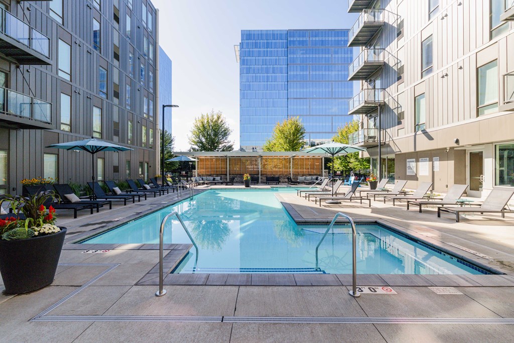 A pool surrounded by chairs and buildings.