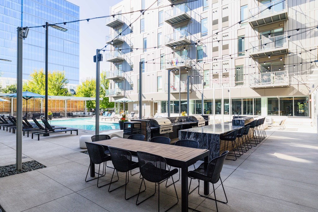 A modern outdoor dining area with tables and chairs is set up in front of a contemporary building.