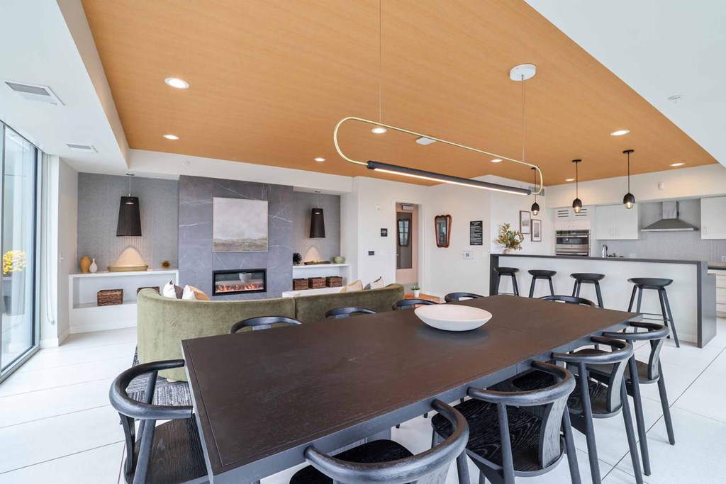 A modern kitchen with a wooden ceiling and a dining table with chairs.