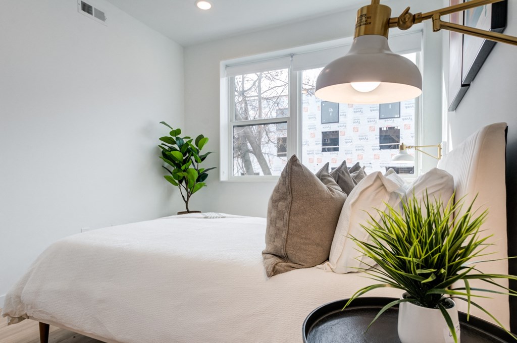 a bedroom with a bed with pillows and a lamp and a window