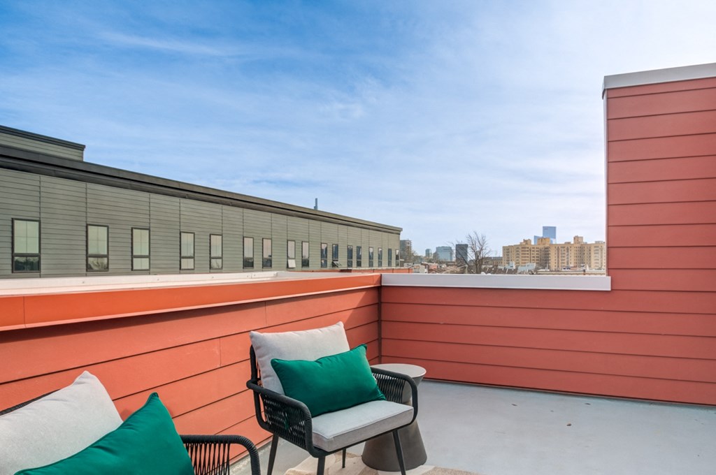 a rooftop patio with two chairs and a view of the city