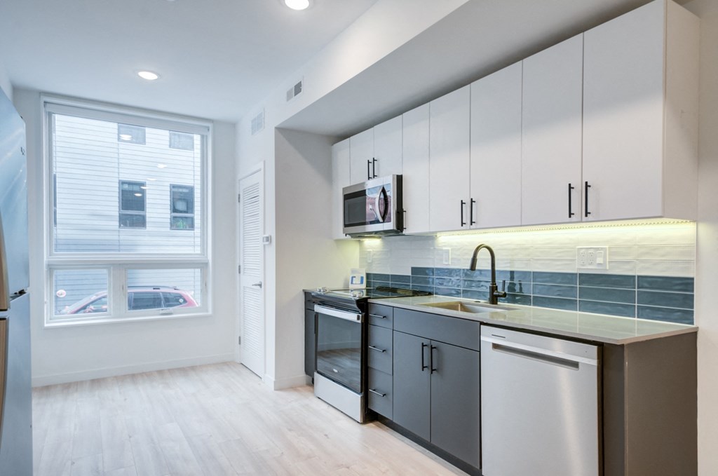 an empty kitchen with white cabinets and a window