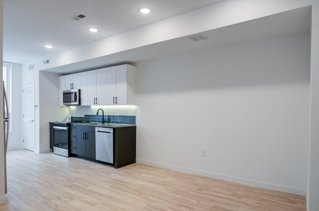 an empty room with a kitchen and a hard wood floor