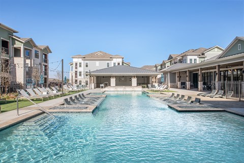 a swimming pool with lounge chairs in front of a building