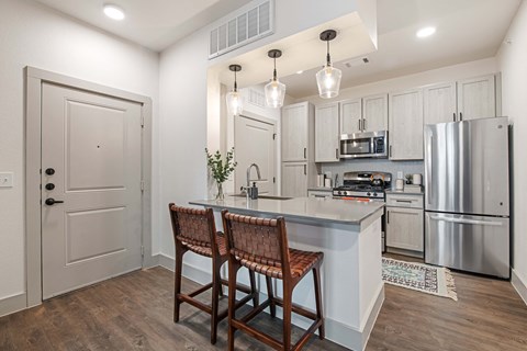 A kitchen with a white door, a wooden table and chairs, and a stainless steel refrigerator.