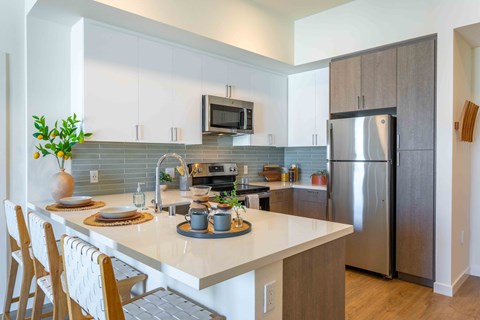 A modern kitchen with a white countertop and stainless steel appliances.