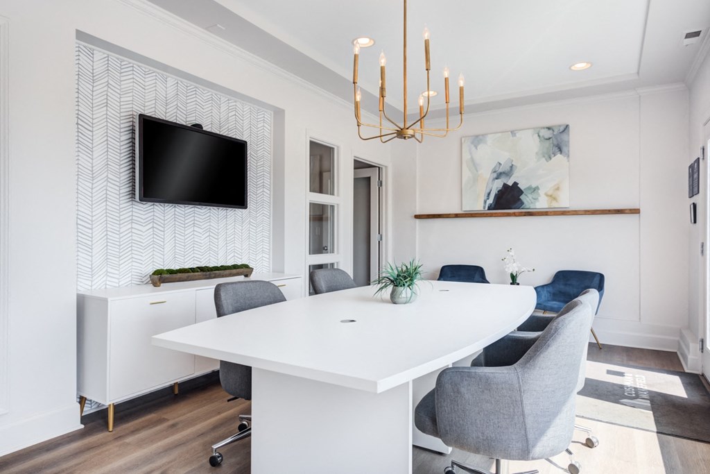 a conference room with a white table and chairs and a tv on the wall