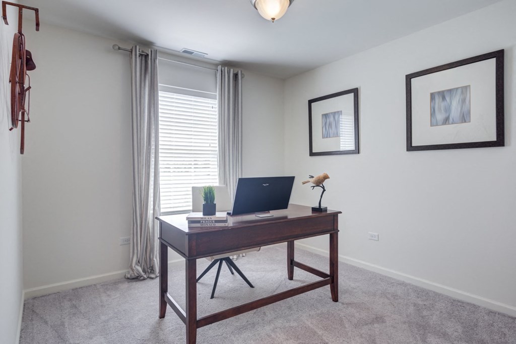 a home office with a laptop on a desk in front of a window