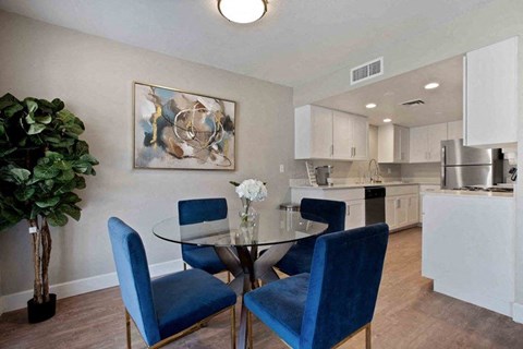 A dining room with a glass table and blue chairs.