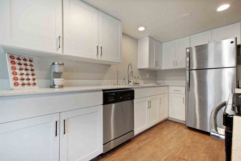 A kitchen with white cabinets and a stainless steel refrigerator.