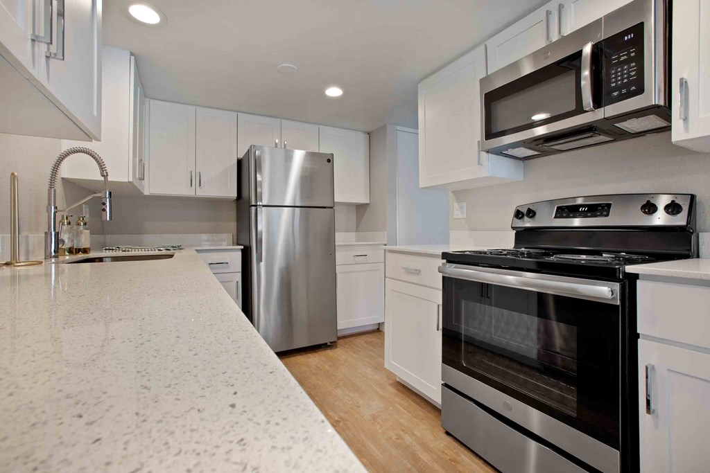 an updated kitchen with stainless steel appliances and white cabinets