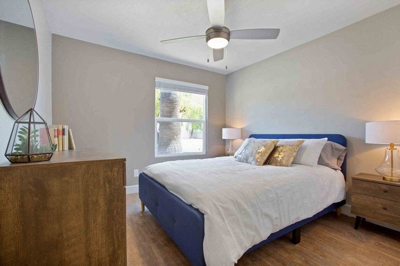 A bedroom with a bed, nightstand, and a mirror on the wall.