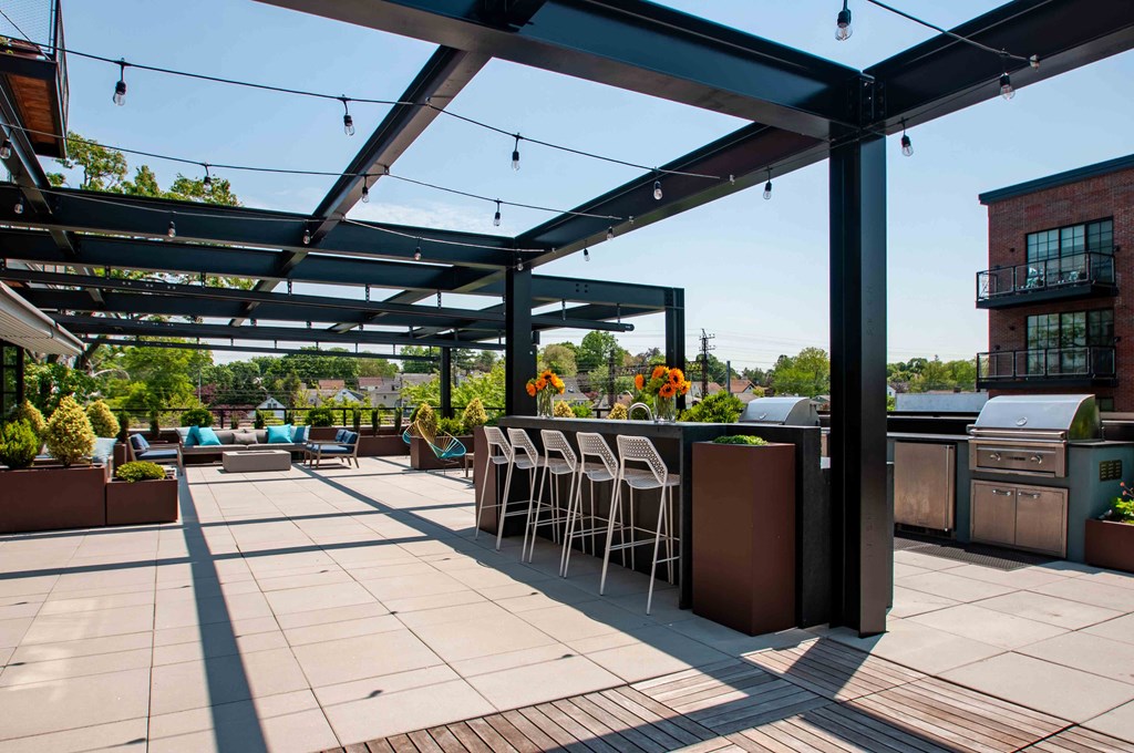 a patio with a bar and chairs under a roof