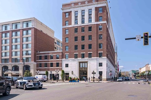 The One Atlantic apartment building with a red brick exterior and white lower level on a sunny city street.