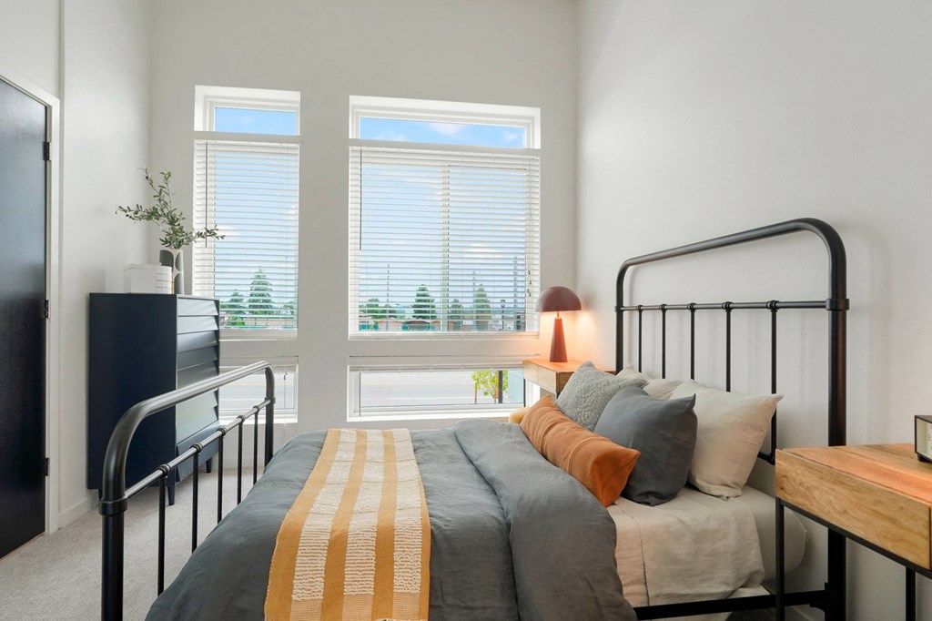 1-BR Apartments in Wheat Ridge, CO - Parallel - Bedroom with Plush Capreting, Bed, Nightstand, Dresser, and Large Window.