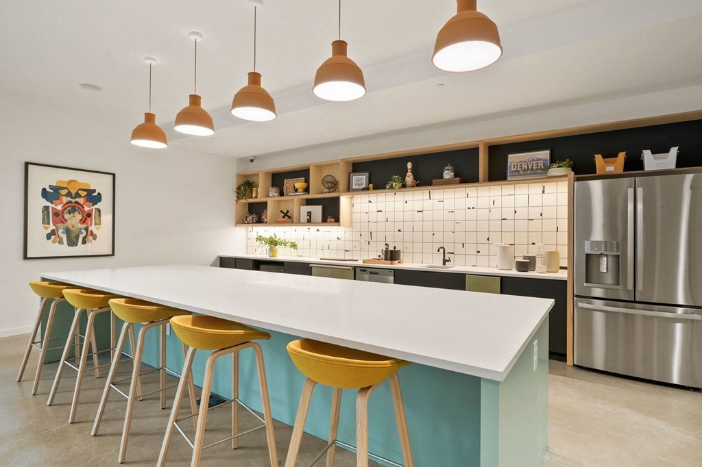 a kitchen with a long white counter and yellow and blue stools