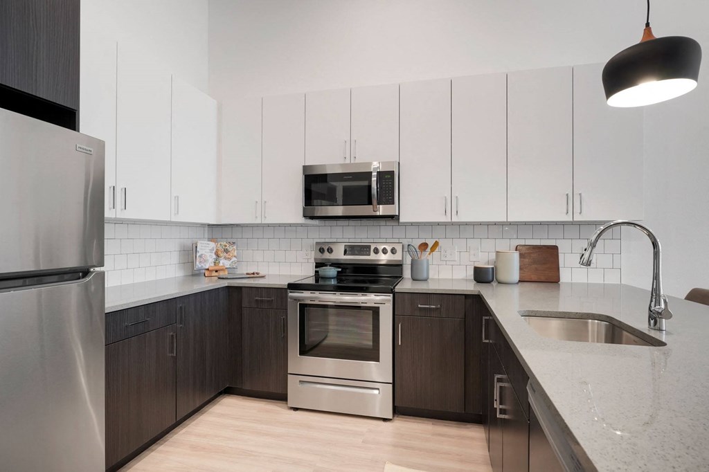 1 Bedroom Apartments In Wheat Ridge, CO - The Parallel - Gourmet Kitchen with White Upper Cabinets and Dark Brown Lower Cabinets, White Tile Backsplash, Quartz Countertops, Stainless Steel Appliances, and Luxury Plank Floors