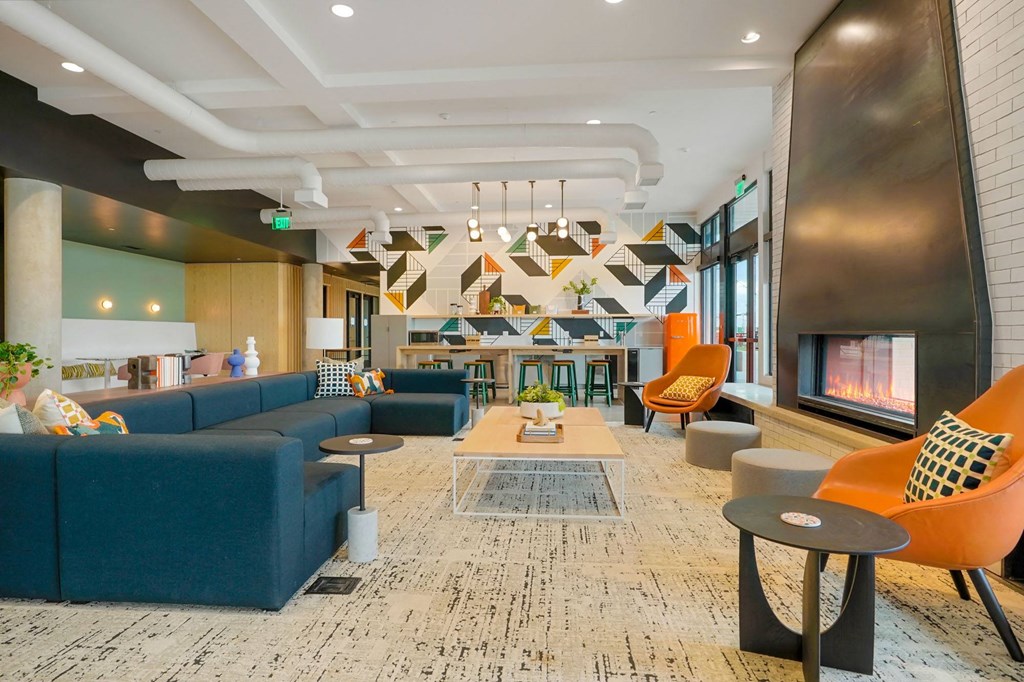 a lobby with blue couches and orange chairs and a fireplace