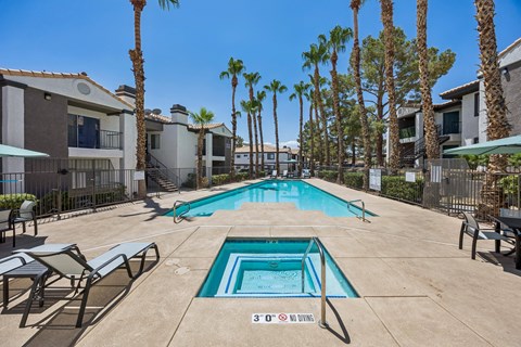 A pool surrounded by palm trees and lounge chairs.