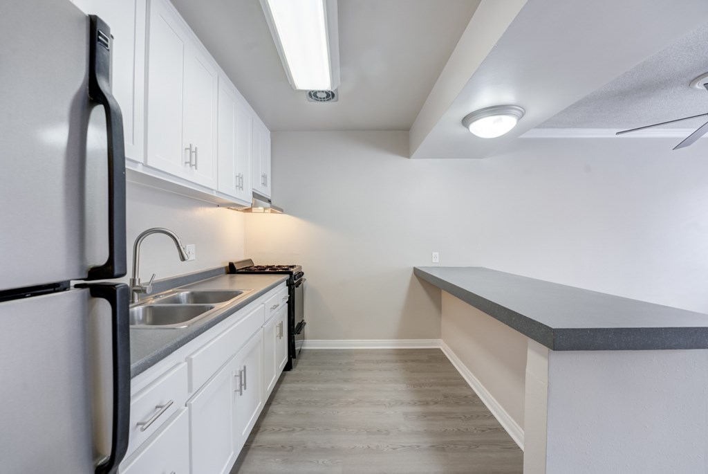 A kitchen with white cabinets and a black refrigerator.