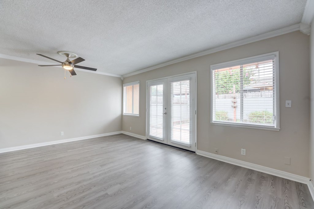 A room with a ceiling fan and sliding glass doors.