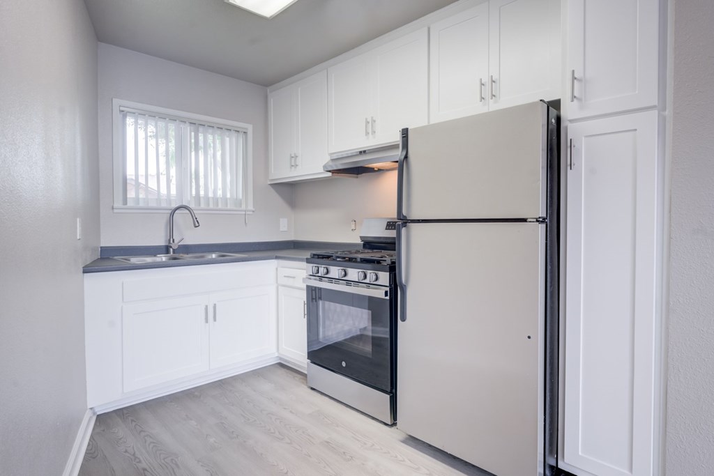 A kitchen with white cabinets and a white refrigerator.