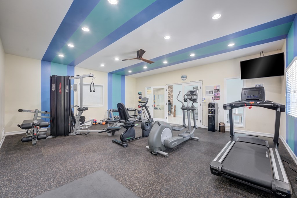 A gym with a variety of equipment including treadmills, weights, and exercise machines.