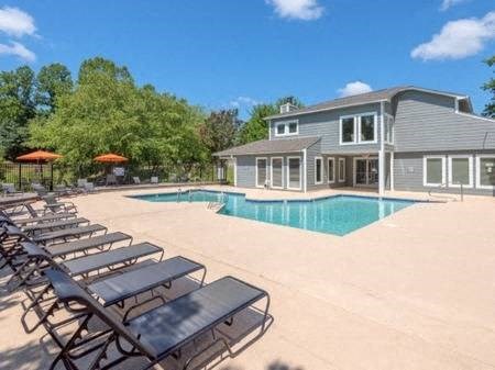a pool with lounge chairs and a house in the background
