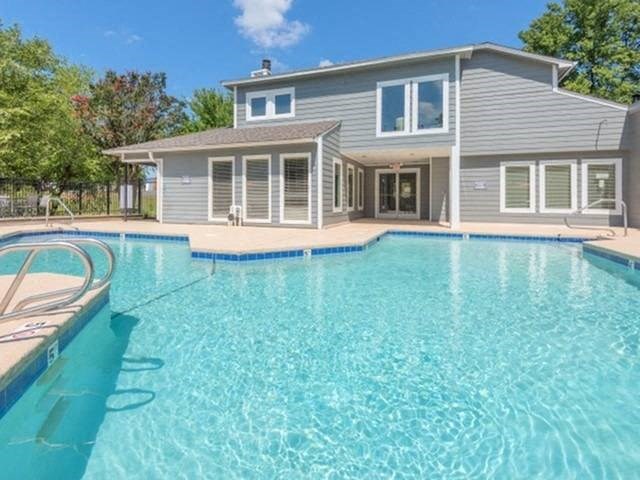 a large swimming pool with a house in the background