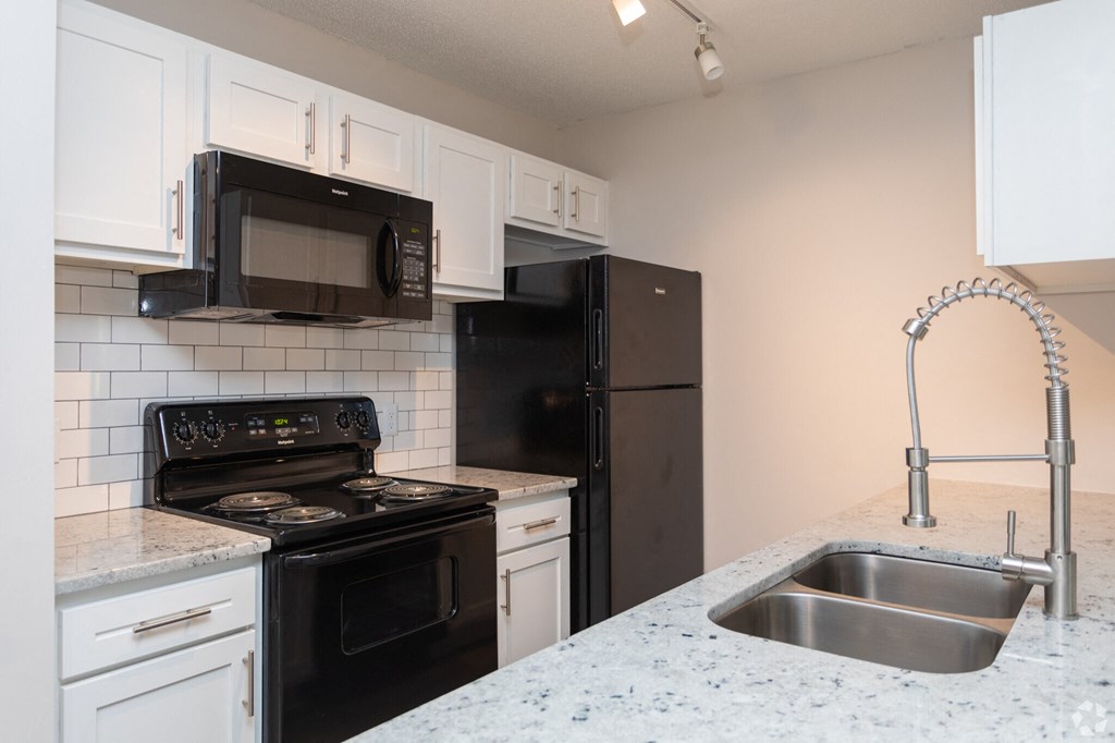 an empty kitchen with black appliances and white cabinets