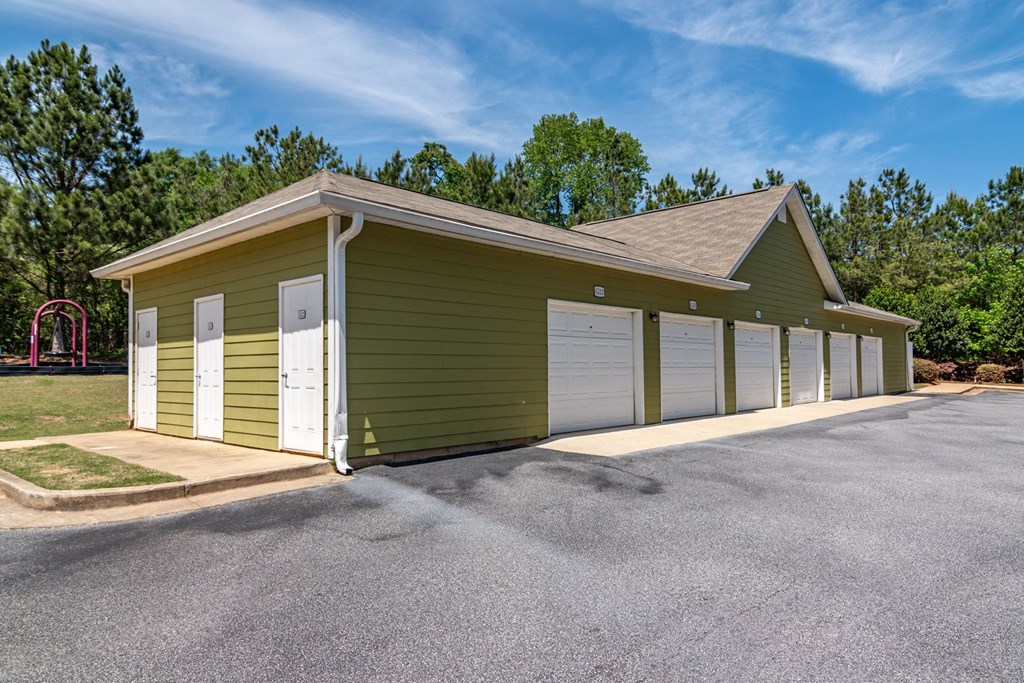 Apartments in Opelika for Rent – The Crossings of Opelika - a row of garages in front of a grassy area with trees in the background