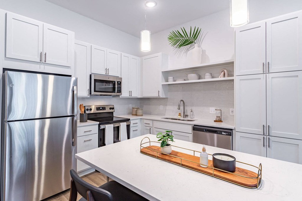 a white kitchen with stainless steel appliances and a white counter top
