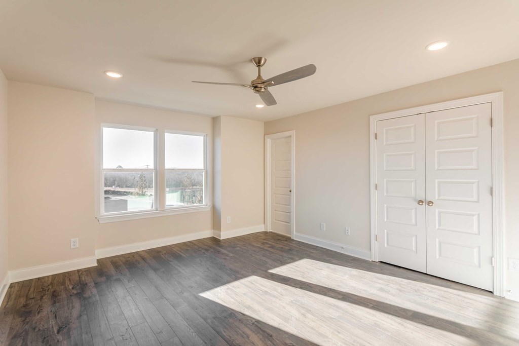 Apartments in Gallatin for Rent - The Gardens at Preston Park - Bedroom with Wood-Style Flooring, Ceiling Fan, and Large Windows
