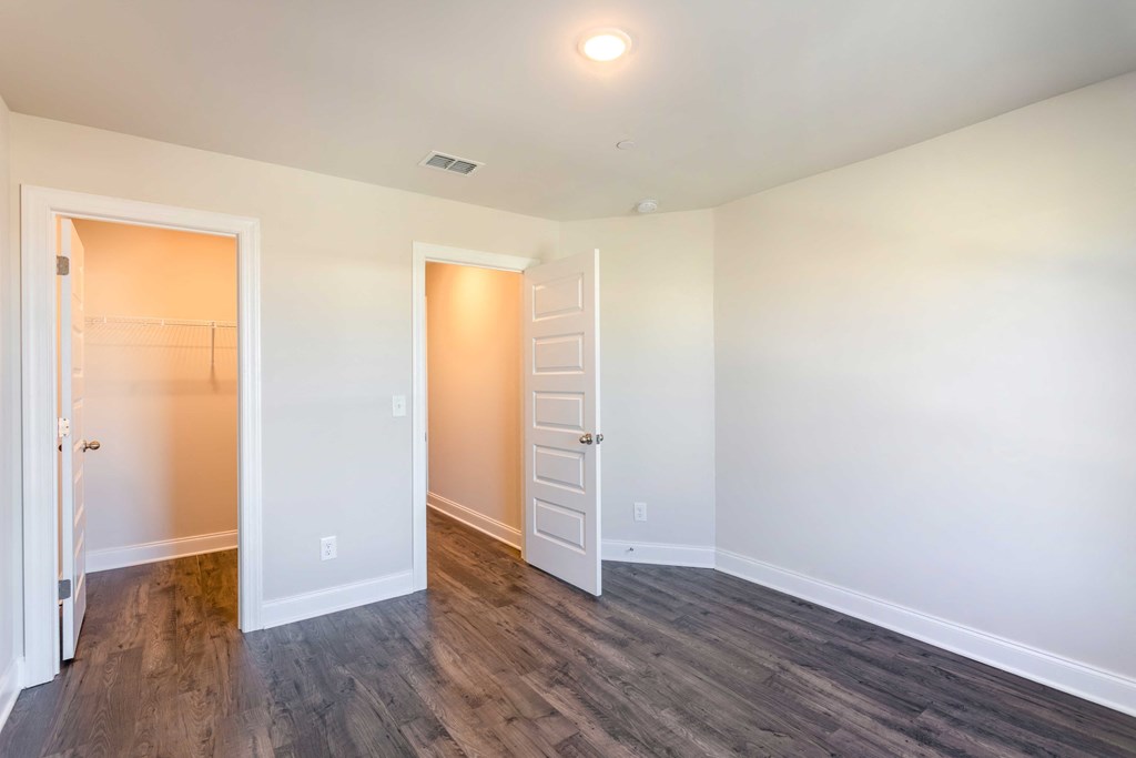 Gallatin, TN, Luxury Apartments - The Gardens at Preston Park - Unfurnished Bedroom with Vinyl Plank Flooring, Large Closet, and White Walls.