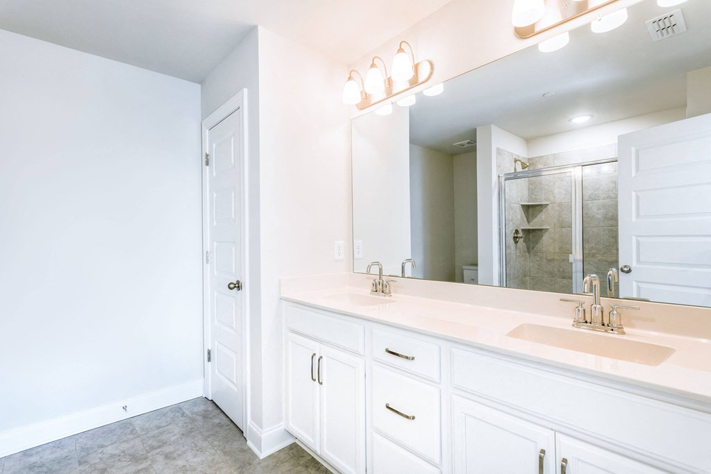 a bathroom with white cabinets and a large mirror