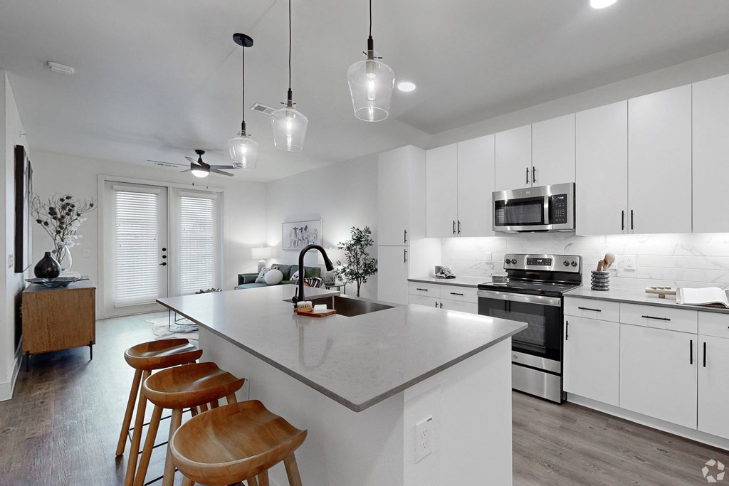 a kitchen with white cabinets and a large island with four stools