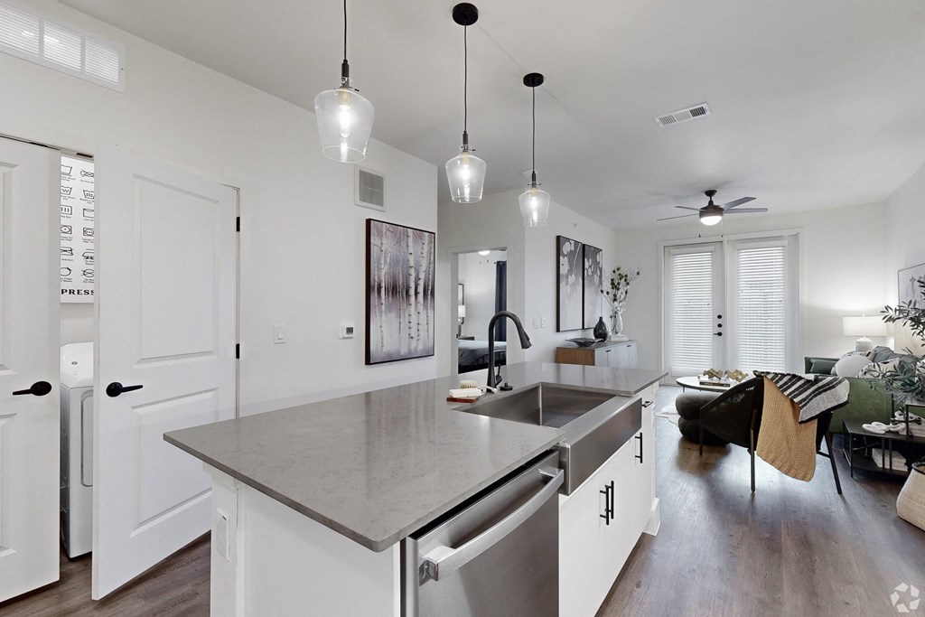 an open kitchen and living room with white cabinets and stainless steel counter tops