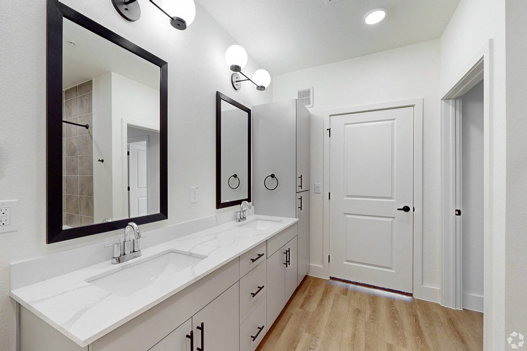 a white bathroom with two sinks and a mirror