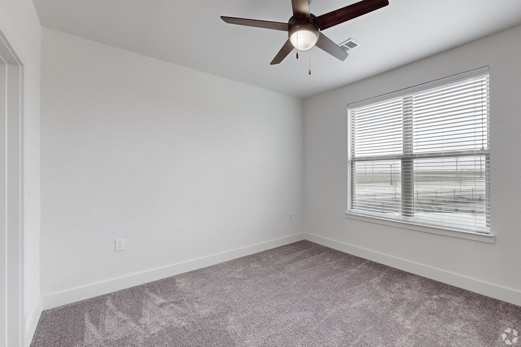 an empty room with a ceiling fan and a window