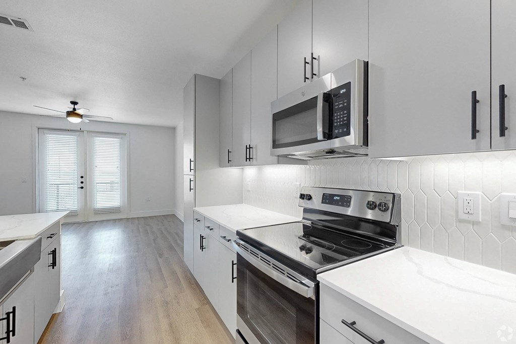 an empty kitchen with white cabinets and stainless steel appliances