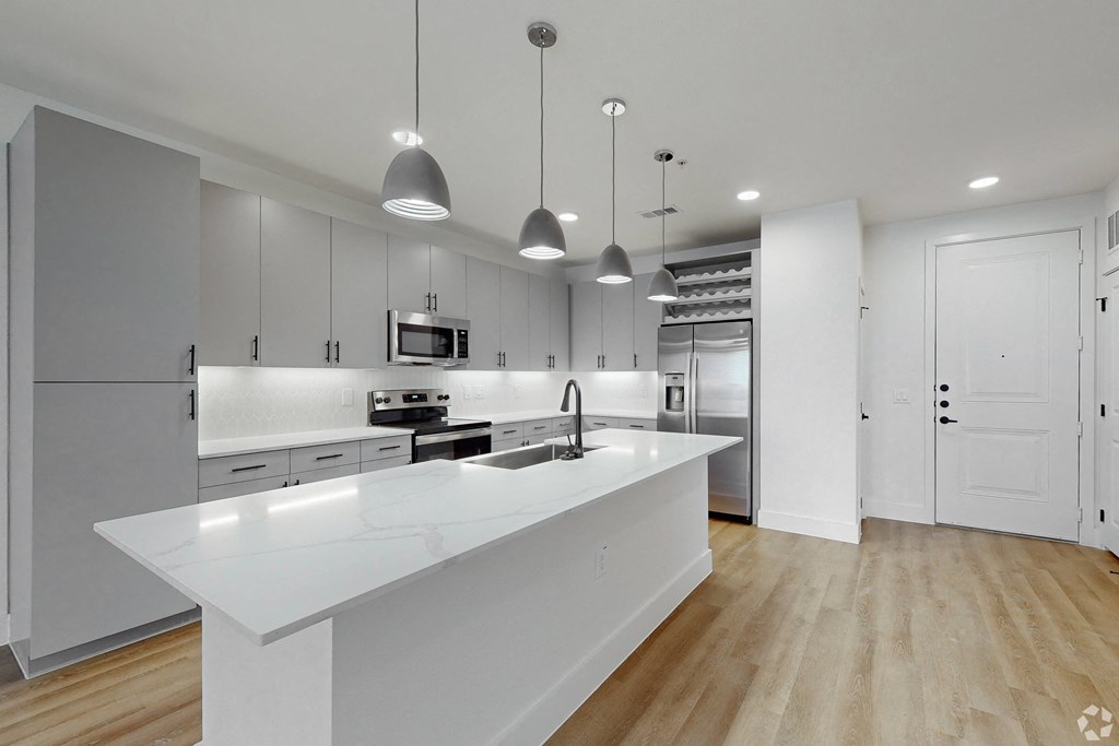 a large white kitchen with stainless steel appliances and white counter tops