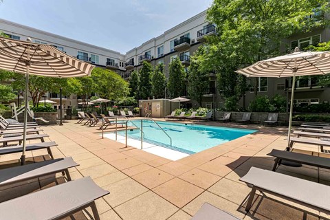 A large outdoor pool area with sun loungers and umbrellas.