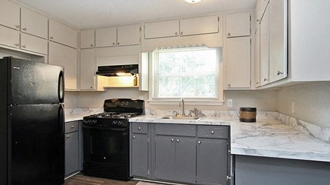 a kitchen with black appliances and white marble counter tops