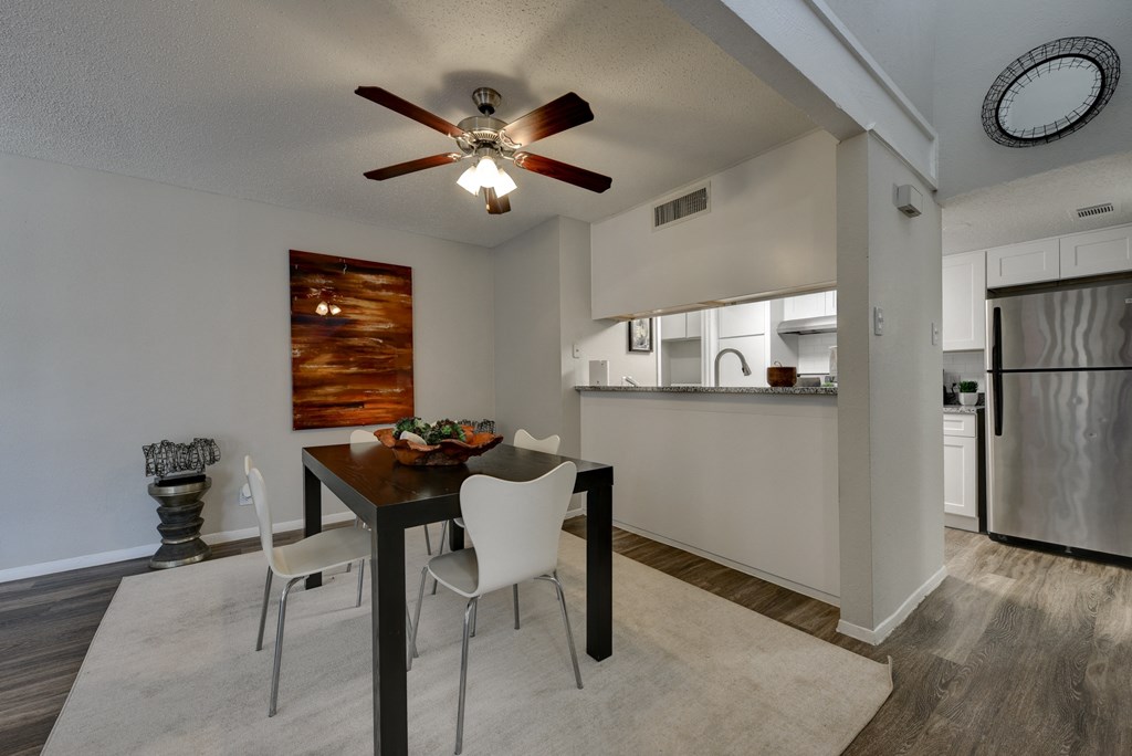 a dining area with a table and chairs and a ceiling fan