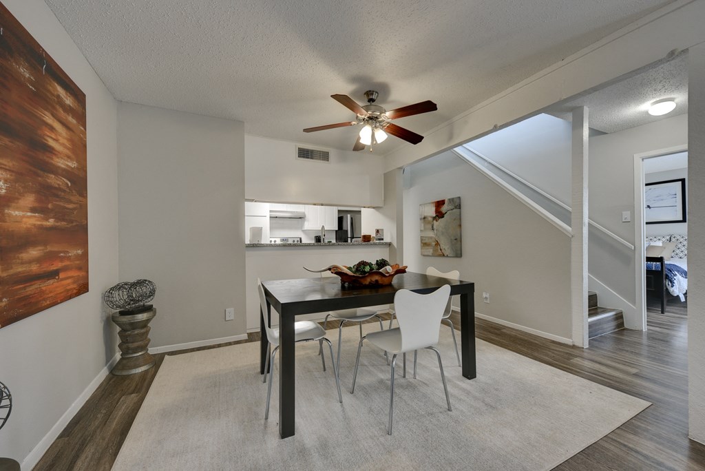 a dining area with a table and chairs and a ceiling fan